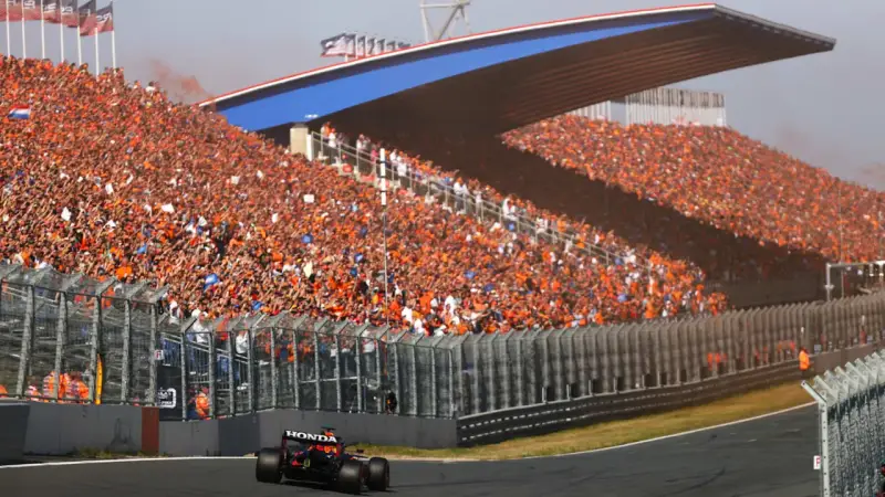 Un coche de Fórmula 1 compite en el Dutch Grand Prix ante una multitud masiva vestida de naranja.