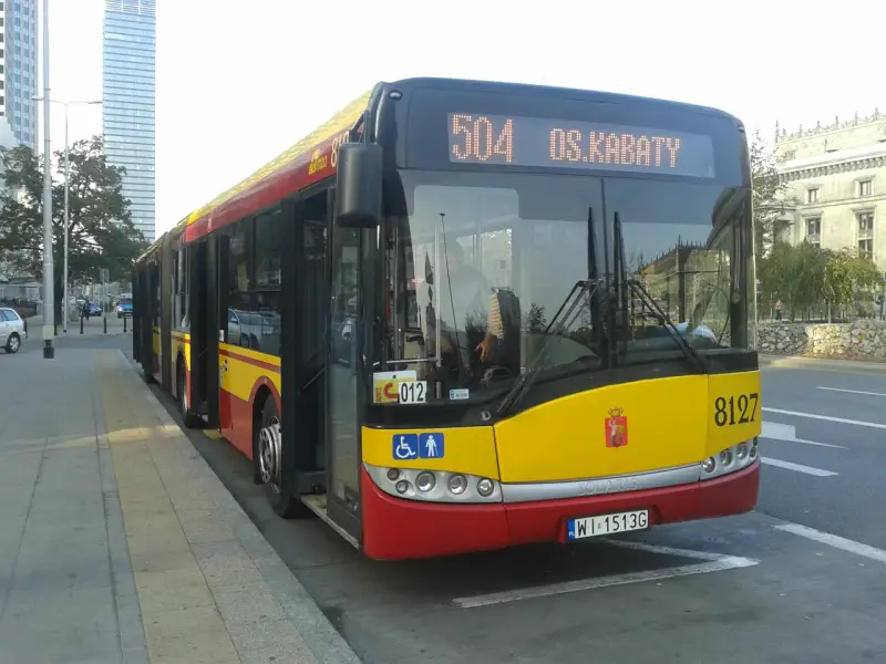 Autobus 504 OS.KABATY z numerem bocznym 8127 stoi na przystanku. W tle widać nowoczesne budynki.