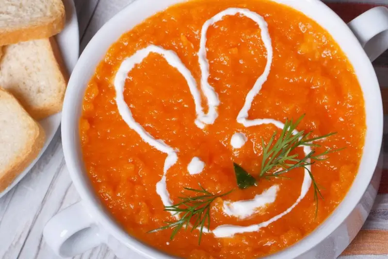 Pomarańczowa marchwianka z ryżem na biegunkę, ozdobiona śmietaną w kształcie królika. Podana z grzankami.