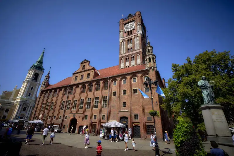 Ratusz Staromiejski w Toruniu z wieżą zegarową i pomnikiem Kopernika na Rynku Staromiejskim.
