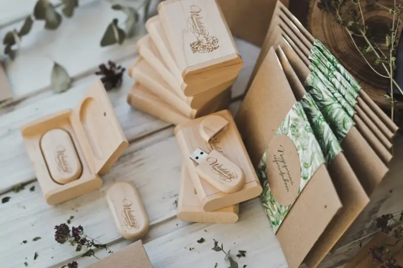 Drewniane pendrive'y z grawerem "Wedding" i koperty z motywem roślinnym. Personalizowane upominki dla gości od pary młodej to klucz do sukcesu.