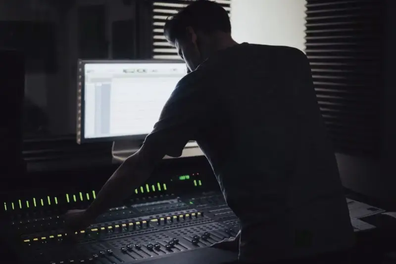 Un ingénieur du son ajuste la console, créant un mixage audio de qualité mp3 320 kbps.