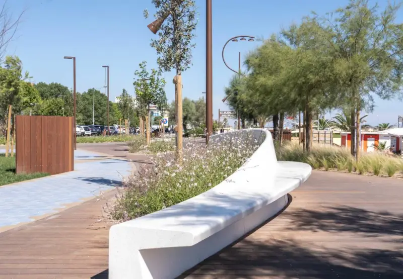 Passeggiata moderna con panchina bianca e fiori sulla bellariva di Rimini.