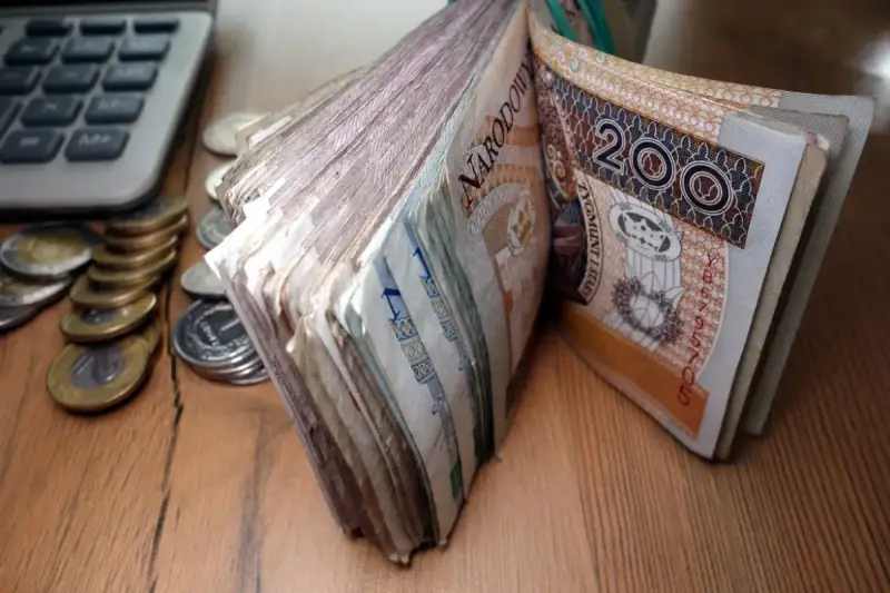 Stos banknotów 200 zł i monet obok kalkulatora. Czy to zapowiedź świadczenia pielęgnacyjnego 2026?