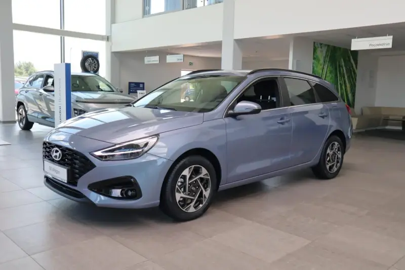 Niebieski Hyundai i30 Wagon z 2015 roku stoi w salonie samochodowym.