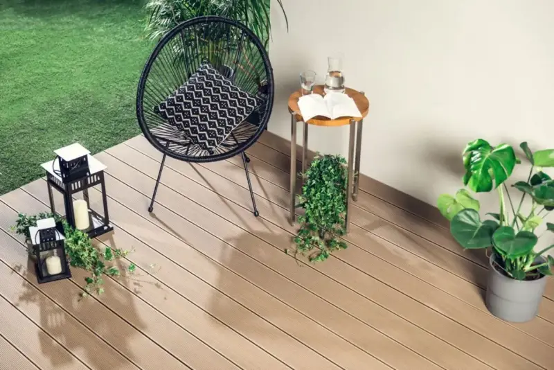 Drewno kompozytowe to świetny pomysł, czym wyłożyć balkon. Wygodne krzesło, stolik i rośliny tworzą przytulną przestrzeń.