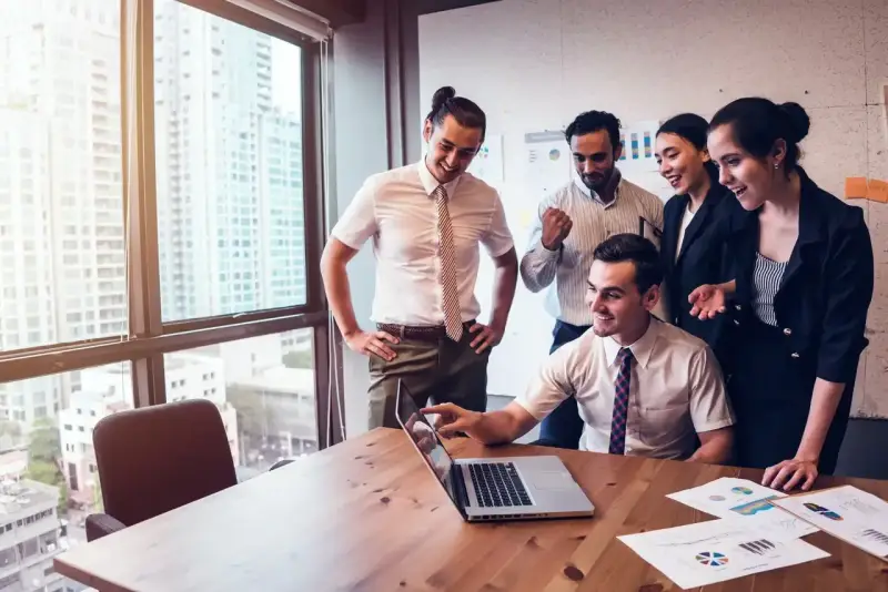 Zespół świętuje sukces. Mężczyzna, który jest business development managerem, wskazuje na ekran laptopa.