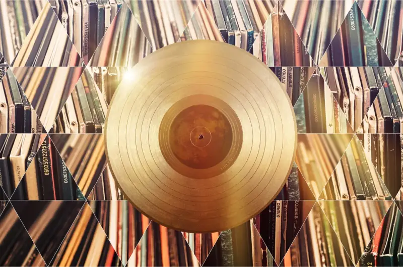 Złota płyta winylowa na tle stosów albumów. Czy to symbol tego, kto sprzedał najwięcej płyt w historii?