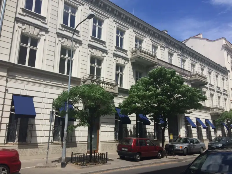 Kamienica z balkonami i niebieskimi markizami. Zastanawiasz się, dlaczego koszt czynszu w blokach z 2026 roku jest wyższy niż w kamienicach?