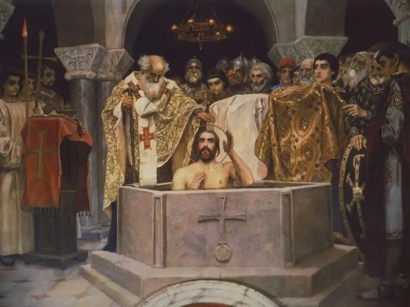 Chrzest Jezusa w Jordanie, uroczysta ceremonia w obrządku ortodoksji. Kapłan błogosławi młodzieńca w chrzcielnicy, otoczeni przez wiernych.