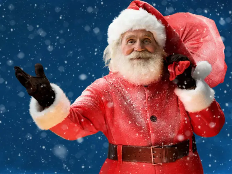 Der Weihnachtsmann mit seinem roten Mantel und Sack winkt fröhlich im Schnee. Ja, es gibt den Weihnachtsmann!