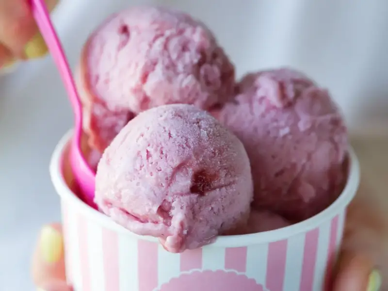 Różowe lody w kubeczku, z różową łyżeczką. Zastanawiasz się, ile kalorii mają lody?