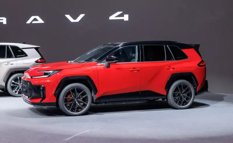 Czerwony, tani SUV z czarnym dachem i felgami, prezentowany na wystawie obok białego modelu.