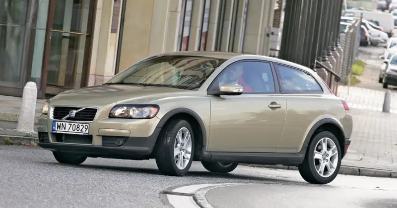 Złoty Volvo C30 z polskimi tablicami rejestracyjnymi WN 70829 jedzie po miejskiej ulicy.