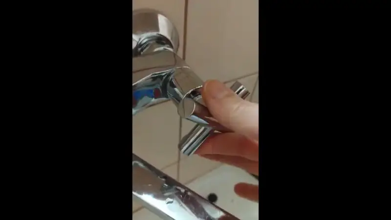 Dłoń odkręca chromowany kurek z baterii prysznicowej. Prosty poradnik, jak zdjąć kurek z kranu.
