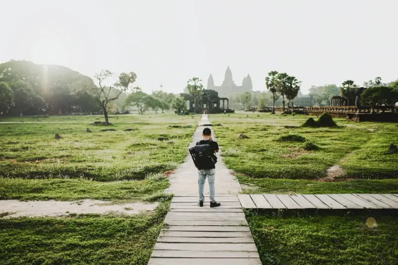 Chłopiec z plecakiem idzie ścieżką do Angkor Wat, jednego z cudów największego kontynentu na ziemi.