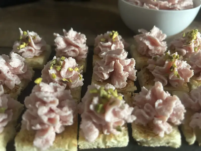 Deliziosi crostini con mortadella, stracciatella e pistacchi, pronti per un aperitivo gustoso.