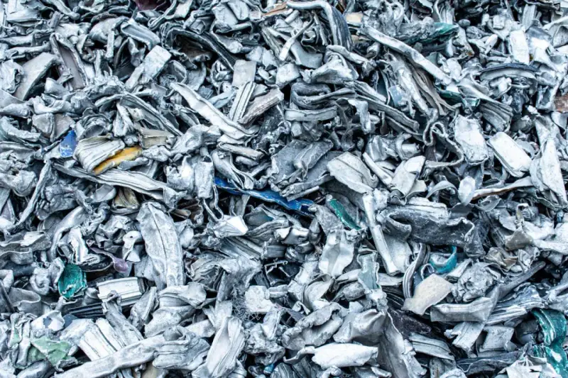 Góra poskręcanego, poszarpanego złomu metalowego, gotowego do recyklingu metalu. Widać fragmenty niebieskiego i żółtego plastiku.