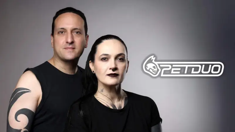 Un hombre y una mujer con tatuajes posan juntos. El logo de PETDUO aparece a la derecha.
