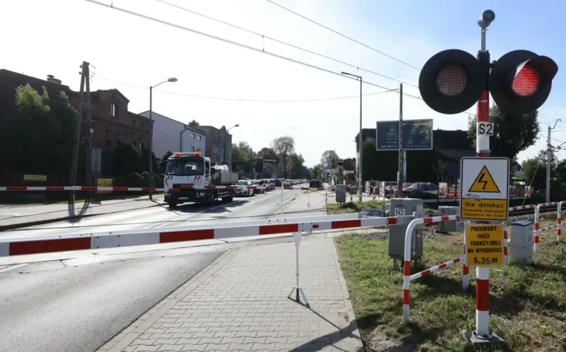 Przejazd kolejowy z zaporami i czerwonymi światłami. Samochód ciężarowy czeka na przejazd.