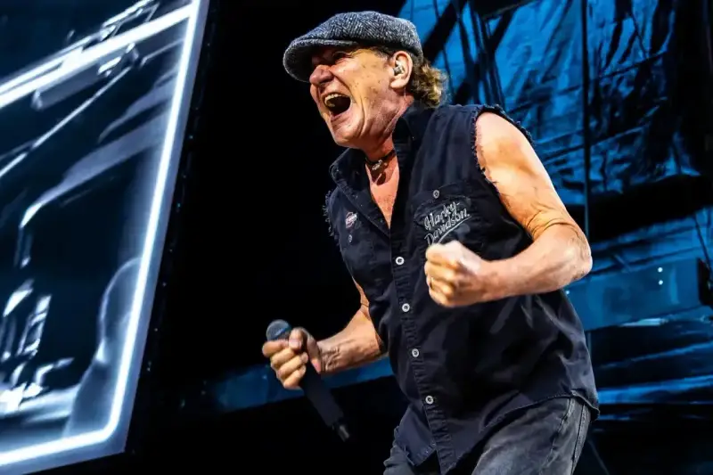 Brian Johnson z AC/DC w Polsce, w szczytowej formie, śpiewa z mikrofonem w dłoni.