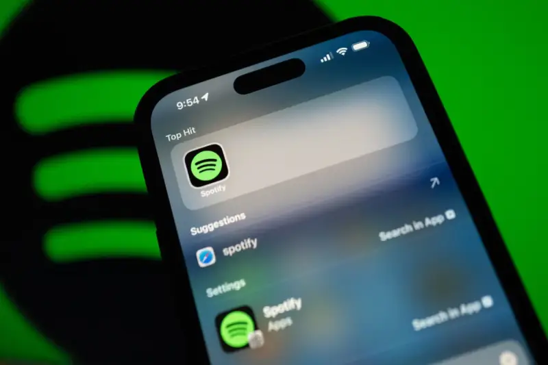 Telefon z aplikacją Spotify, sugerującą muzykę w jakości **spotify lossless**. Zielone logo Spotify w tle.