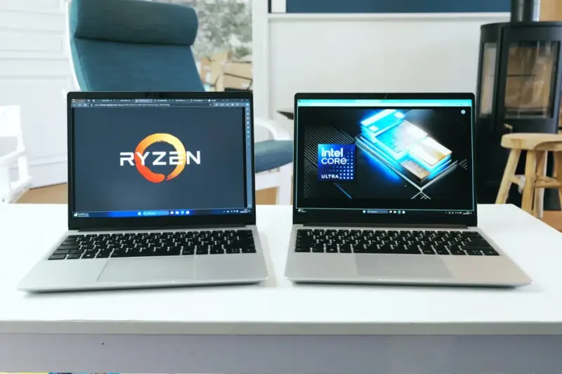 Deux ordinateurs portables côte à côte, l'un affichant le logo Ryzen, l'autre le logo Intel Core Ultra. Un **framework computer** pour chaque processeur.