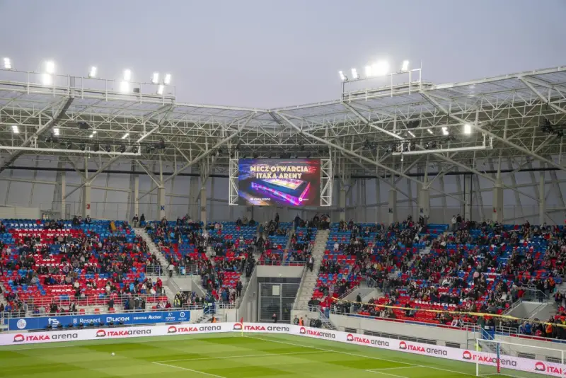 Widownia na stadionie Odra Opole podczas meczu otwarcia. Kolorowe trybuny i wielki ekran z napisem "Mecz otwarcia Itaka Areny".