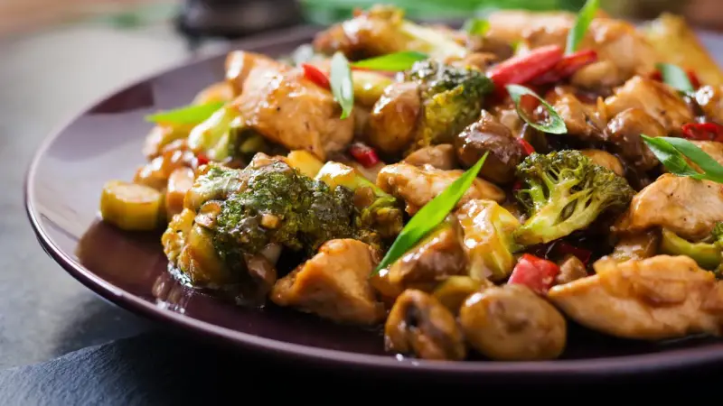 Pyszny stir fry z kurczakiem, brokułami i grzybami w sosie. Danie wygląda apetycznie i jest bogate w kolory.