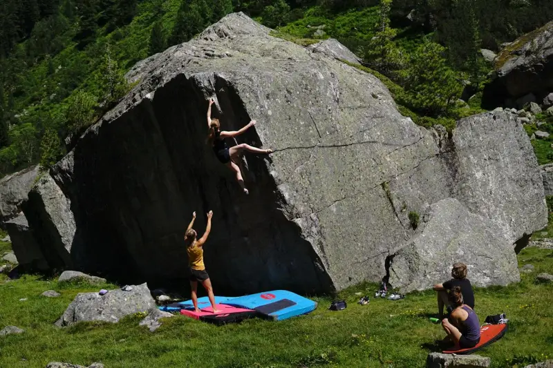 Zwei Frauen klettern an einem Felsen, eine oben, die andere unten. Das ist, was ist bouldern: Klettern ohne Seil an niedrigen Felsen.