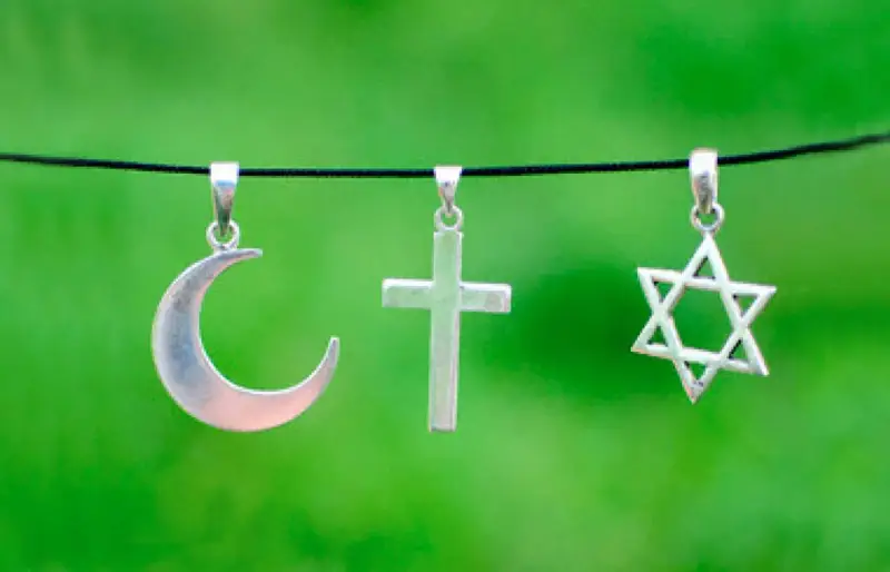 Srebrny półksiężyc, krzyż i gwiazda Dawida wiszą obok siebie. Symbolika islamu, chrześcijaństwa i judaizmu w harmonii.