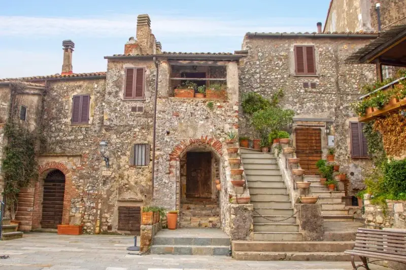 Un angolo di **Toscana, cosa vedere: borghi** antichi con case in pietra, scale fiorite e un'atmosfera senza tempo.