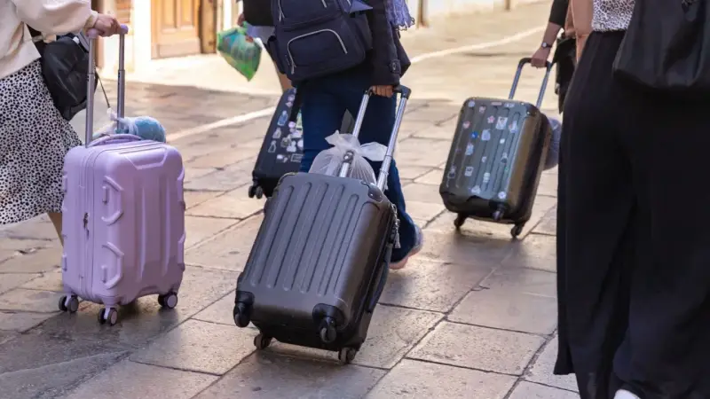 Ludzie z walizkami na kółkach, zastanawiający się, ile dopłata za bagaż Ryanair.