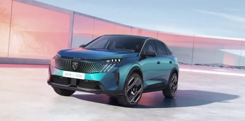 Nowy Peugeot E-3008 2021 w turkusowym kolorze, zaparkowany przed nowoczesnym budynkiem z różowymi akcentami.