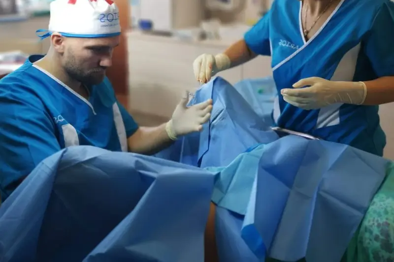 Chirurg i asystentka w rękawiczkach przygotowują się do zabiegu. Zdjęcia nieudana labioplastyka mogą pokazywać takie momenty.