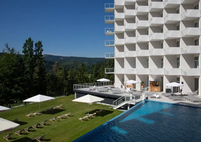 Nowoczesny hotel Crystal Mountain Resort z basenem i leżakami na trawie, otoczony zielonymi wzgórzami.