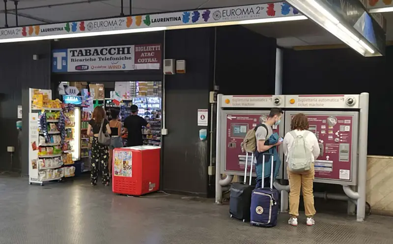 Przystanek autobusowy w Rzymie Ciampino. Ludzie kupują bilety i artykuły w sklepie.