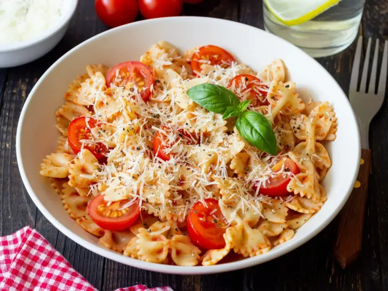 Pyszny makaron farfalle z pomidorkami koktajlowymi i parmezanem, idealny na kolację.
