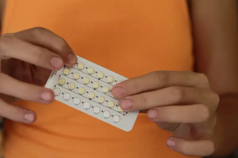 Manos sostienen un blíster de pastillas anticonceptivas. Me he quitado el anillo y no me baja la regla, ¿será por esto?