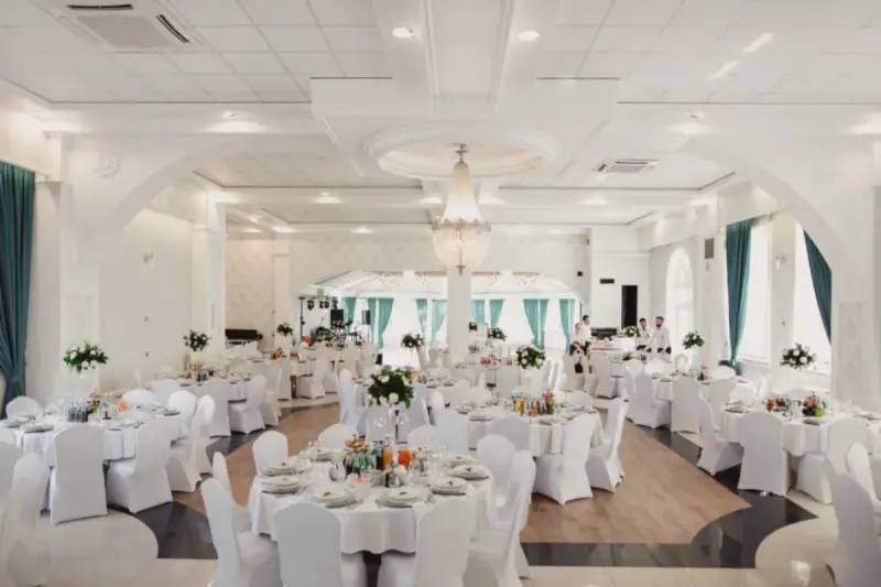 Elegancka sala weselna z białymi pokrowcami na krzesłach, sugerująca rezygnację z modeli tiffany na rzecz prostoty i klasy.