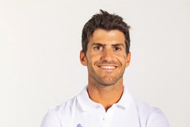 Portrait souriant de Kévin Peponnet, athlète français en polo blanc, sur fond clair.