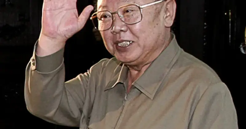 Kim Jong Il w okularach, machający ręką.
