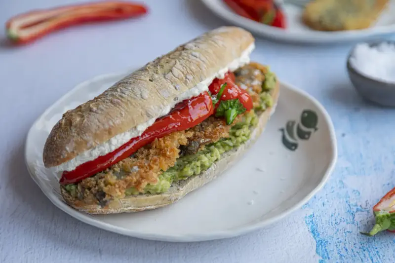 Pyszna kanapka ze śledziem, awokado i pieczoną papryką na chrupiącej bułce. Idealna na szybki lunch.