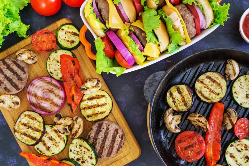 Pyszne przekąski na grilla: burgery, grillowane warzywa (cukinia, bakłażan, papryka, cebula, pomidory) i pieczarki. Idealne na letnie spotkania.