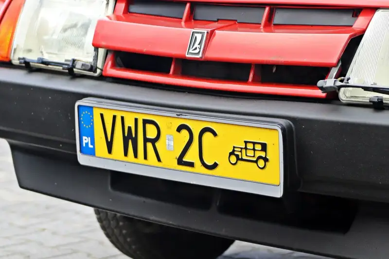 Czerwony grill z logo, reflektor i żółta tablica rejestracyjna z napisem VWR 2C oraz symbolem starego samochodu. To jest rejestracja dw.