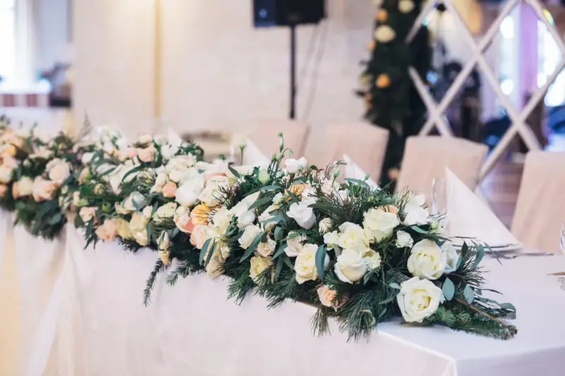 Eleganckie kwiaty na wesele zdobią stół, tworząc romantyczną atmosferę. Bukiet z róż i zieleni.