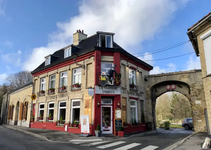 Façade de la Taverne Vauban à Bergues, avec une enseigne et une décoration de cycliste.