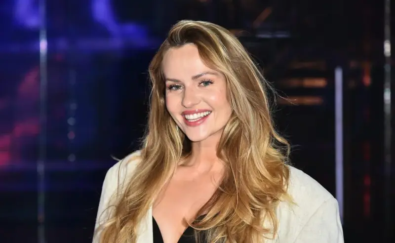 Uśmiechnięta Żaneta Rosińska, której wiek dodaje jej uroku, w białej marynarce i czarnej kreacji.