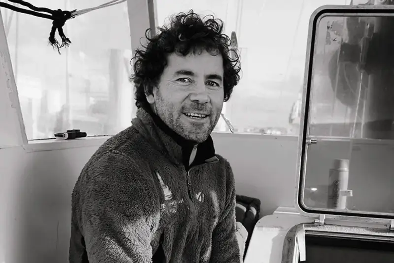 Sébastien Roubinet, un aventurier souriant, pose à l'intérieur d'un bateau, prêt pour sa prochaine expédition.