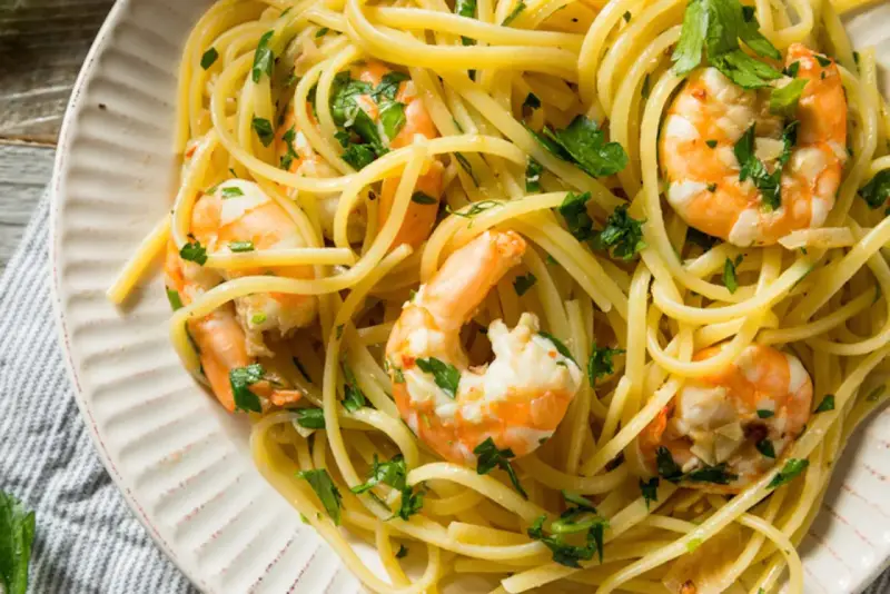 Un piatto invitante di pasta con gamberetti, condita con prezzemolo fresco e un filo d'olio.